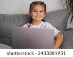 Small photo of Portrait of beautiful little girl using smart devise. Five year old girl open and use laptop