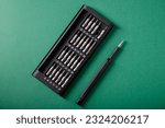 A set of precision screwdrivers for disassembling phones, on a green background, top view