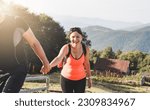 Small photo of A man helps a happy woman climb the mountain. The concept of tourism, hiking and active pastime weekends and holidays