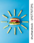 Small photo of Burger with french fries laid out around on blue backdrop. Creative colorful burger