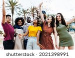 Young multiracial hipster people having fun in summer party celebration - Group of young friends laughing and celebrating all together while throwing coloured confetti at weekend event outdoors