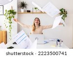 Young excited fun entrepreneur woman throwing papers celebrating business success at office