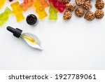 Gummy bears, cannabis cookies and cbd oil dropper in white backdrop. THD or cbd sweets in form of gelatine gummi bears and essential oil pipette background: calming edible food supplements