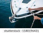 Small photo of Man s hand with boat rope. Yachtsman moors his motor boat at jetty. Close up hands and bow of the boat.