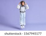 Portrait of child boy in protective white suit while jumping up isolated over purple background