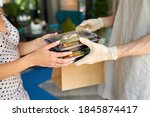 Small photo of cropped female client make order in restaurant and take it by waiter in protective gloves. give away orders, food in containers. close-up
