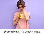 Cute sleepy woman having no enough sleep, holding yellow mug in hands, coffee in the morning. Adult woman need go at work or university. Isolated purple background