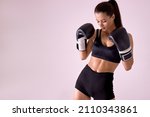 Small photo of attractive european fitness woman with boxing gloves posing in defiant and competitive fight attitude, fighter concept isolated in studio background. strong lady in black sportswear looking down
