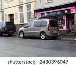 Small photo of 20th February 2024- A bronze Peugeot Partner Tepee Allure, five door MPV, parked on a street in the town center at Carmarthen, Carmarthenshire, Wales, UK.