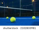 Small photo of Selective focus. Three paddle tennis balls on the surface of a blue paddle tennis court. Sports concept.