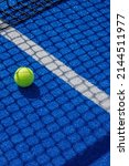 Small photo of paddle tennis ball in the shade of the net of a blue paddle tennis court racket sports concept