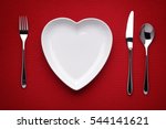 plate in shape of heart, table knife and fork on red 