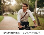 Man enjoying music using earphones while commuting to office on a bicycle. Businessman biking to office while listening to music.