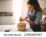 Woman decorating chocolate cake in the kitchen. Female chef making a cake at home.