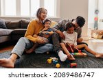 Small photo of Young parents playing with their son and daughter in the living room. Mom and dad having fun with their children during playtime. Family of four spending some quality time together at home.