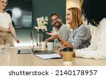 Small photo of Cheerful businesswoman having a discussion with her colleagues in a boardroom. Group of happy businesspeople sharing ideas during a meeting in a modern workplace.