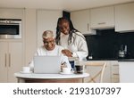 Small photo of Cheerful senior couple shopping online with a laptop and a credit card. Happy mature couple placing an online order at home. Carefree pensioners spoiling themselves after retirement.
