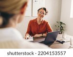Small photo of Happy hiring manager smiling while interviewing a job candidate in her office. Cheerful businesswoman having a meeting with a shortlisted job applicant in a creative workplace.