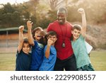 Small photo of School kids celebrating with their coach on a sports field. Elementary school children cheering after a training session. Sports and fitness in primary school.