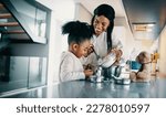 Small photo of Woman teaching her daughter how to mix flour for baking. Happy mom making a cake with her daughter in the kitchen. Mother passing a family recipe to her child.