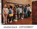 Small photo of Primary school students waiting in line outside their classroom. Group of children eagerly waiting to start class in the morning. Elementary age kids standing together in school.