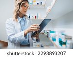 Small photo of Doctor using a tablet while standing in a pharmacy. Female healthcare worker processing online prescriptions in a hospital dispensary. Woman working in a chemist.