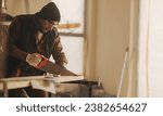 Small photo of Building contractor renovating a kitchen, using a saw to cut wood. He is focused on the home improvement project, undertaking remodeling and refurbishment work with precision.