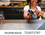 Customer making wireless or contactless payment using credit card. Smiling cashier accepting payment over nfc technology.