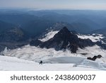 Mountain Climber standing on a Glacier on Mount Rainier, looking out over the peaks and valleys of the Cascade Range