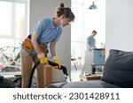 Cleaning service workers working in apartment in team, they vacuuming furniture and cleaning the room
