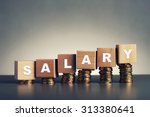 salary text written on wooden block with stacked coins on grey background