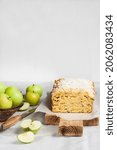 Small photo of Apple and coconut oaf cake on wooden cutting board and apples in a vase. Copy space