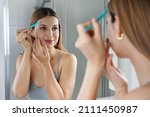 Small photo of Facial hair removal. Beautiful young woman shaving her face by razor at home. Pretty woman using razor on bathroom.