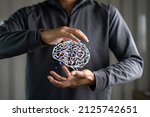 Small photo of Close up of businessman hand holding brain in palm, Virtual reality man with symbol neurons in the brain. Concept of idea and innovation, copy space.