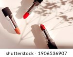 Fashion colorful lipsticks sun shadows from flowers on beige background flat lay top view. Beauty and cosmetics background. Decorative cosmetics makeup women's lipstick beauty brand product design