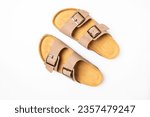 Small photo of Leather beige sandals birkenstocks on white background top view flat lay. Unisex summer shoes, genuine leather flip flops with cork soles. Stylish fashion footwear, mockup for design