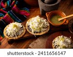 Small photo of Sopes. Mexican typical food prepared with flattened fried corn dough covered with refried beans, green or red sauce, lettuce, cheese, onion and sour cream. Mexican antojitos.