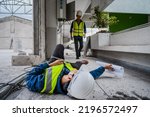 Small photo of Accident at work, an Asian engineer or electrician is electrocuted to the ground. A colleague engineer rushed in for help or assistance. Concept of accident at a construction site.