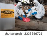 Small photo of A team of two chemists, wearing PPE suits and gas masks, recover a deadly chemical spill on the factory warehouse floor. Correct disposal of chemical spills in industrial plants.