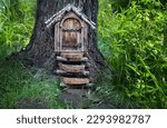 Small photo of tree with magical wooden fairy door in forest, abstract natural background. Fairy tale tree house in mystery woodland, pixie and elf home. Atmospheric nature image. template for design