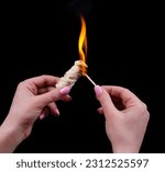 Small photo of Ignite with a match in a female hand a firebrand for a fireplace on a black background