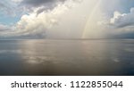 Small photo of A rainbow reflected across a body of water as sporadic rain showers come to a halt.