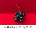Cluster of moon drops dark purple grapes on duotone red crimson background. Wine production harvest vitamins healthy lifestyle concept. Creative food poster with copy space