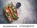 Two fresh baguette sandwiches with meat, tomato, cucumber and arugula on a gray background.