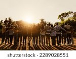 Back view of happy multigenerational people having fun in a public park during sunset time - Community and support concept 