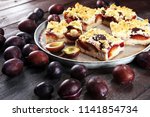 Small photo of Rustic plum cake on wooden background with plums around