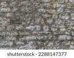 Small photo of Gray real texture of old stone wall. Pattern of shapeless blocks with cement joints between them, covered with black fungus. Vintage architectural background with copy space