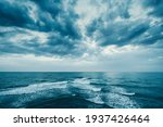 Dark blue clouds and sea or ocean water surface with foam waves before storm, dramatic seascape