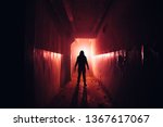 Creepy silhouette with knife in the dark red illuminated abandoned building. Horror about maniac concept.