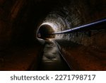 Underground vaulted urban sewer tunnel with dirty sewage.